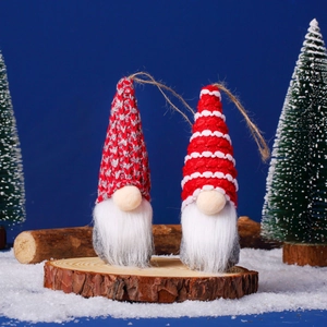Detail of two Christmas gnome ornaments with red knit hats on rustic wood slices
