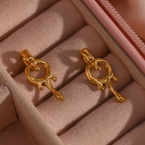 Close-up of golden lava-style stud earrings placed in a pink velvet jewelry box display