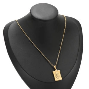 Golden embossed Virgin Mary pendant necklace displayed on a black jewelry bust stand