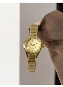 Close-up of gold bangle watch for women with minimalist dial and Roman numeral markers