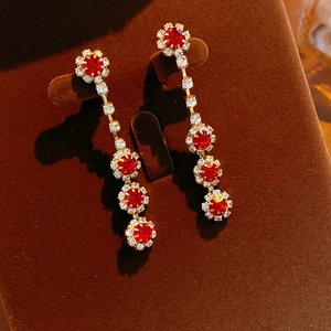 Macro shot of gold floral earrings with red rhinestones and tassels on velvet