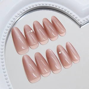 Glittery nude pink cat-eye almond press-on nails with pearl accents on a heart mirror