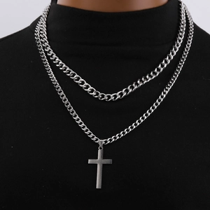 Detail of silver double-layer Cuban chain and cross pendant on black turtleneck