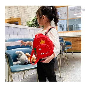Detail view of red mini toddler backpack featuring a cute monster print and side mesh pocket