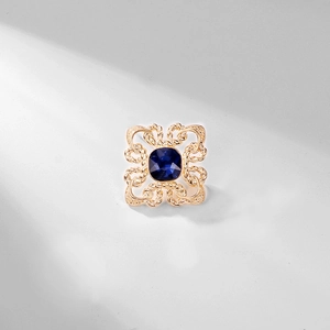Detailed view of vintage gold-toned brooch featuring a deep blue faceted crystal stone