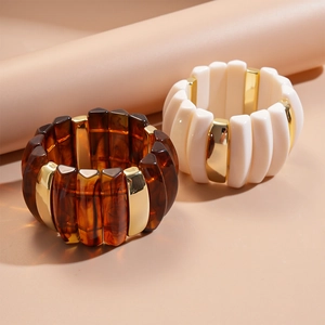 Detail of chunky acrylic stretch bracelets in amber and cream with gold metal accents