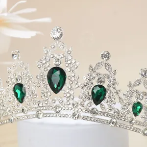 Detail of luxury silver crown with green teardrop gemstones and crystal pavé on white stand
