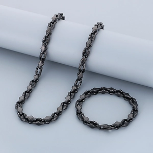 Detail of black geometric stainless steel necklace and bracelet set on a grey pedestal