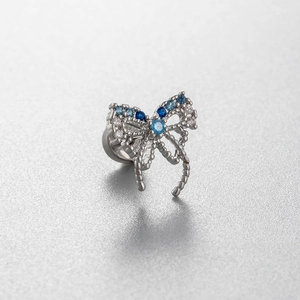Silver bow stud earring with blue gems and titanium steel flat back screw on a grey surface