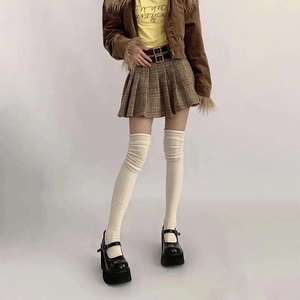 Close-up of cream ribbed over-the-knee socks paired with a plaid skirt and Mary Janes