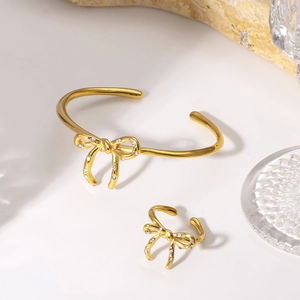 Elegant gold bow jewelry set with crystal-encrusted open cuff bracelet and matching ring