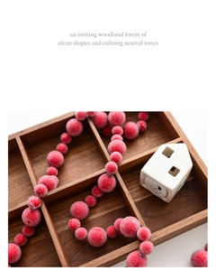 Close-up of frosted red Christmas berry garland on wood tray with snowy texture
