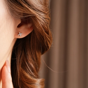 Close-up of silver cross stud earring with micro-pave cubic zirconia on model's ear