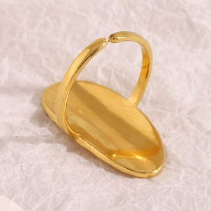 Polished 18K gold plated stainless steel open ring with flat oval surface on textured paper