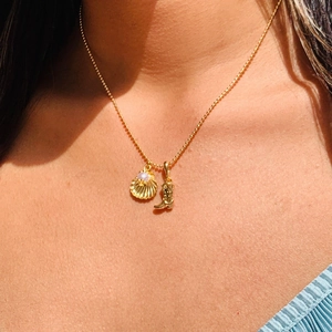 Gold ball chain necklace featuring pearl shell and cowboy boot pendants on a female model