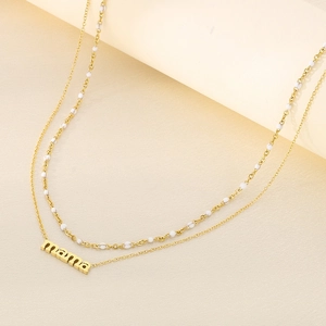 Detail of double-layered gold MAMA pendant necklace with white bead chain and metallic luster