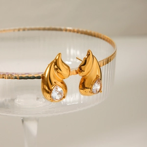 Detail of gold teardrop earrings with crystals hanging on a luxury glass rim