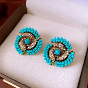 Detailed close-up of bohemian gold floral earrings with turquoise beads and crystals