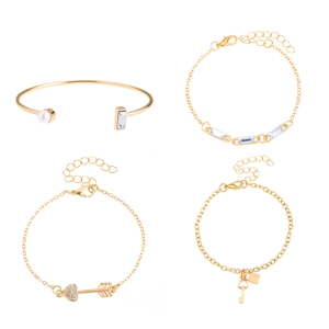 Detail van vier goudvergulde armbanden met hart, sleutel, slot en parel accenten