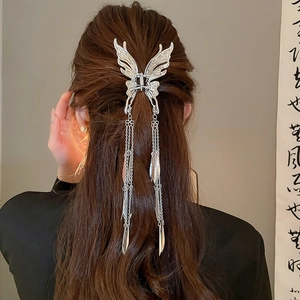 Pince à cheveux papillon argentée avec longs pompons sur de longs cheveux ondulés