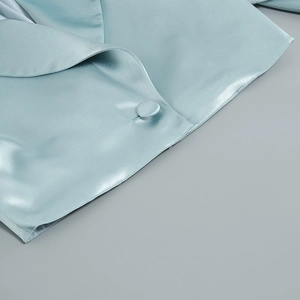 Détail du col en satin bleu clair et bouton recouvert assorti sur l'ensemble chic