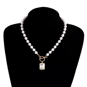 Detail of pearl necklace featuring golden OT toggle clasp and rectangle crystal pendant