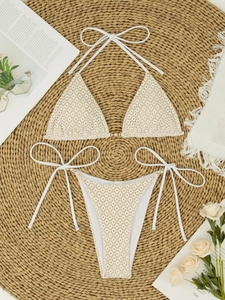 Close-up of white crochet bikini set with pearl accents and gold metal ring detailing