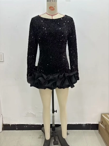 Détail de la robe courte à paillettes noires avec manches longues et ourlet volanté