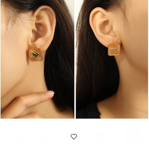 Detail of square gold earrings with radial texture and heart-shaped gemstone inlay