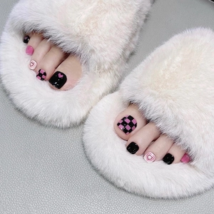Close-up of black and pink press-on toenails with heart and checkered patterns