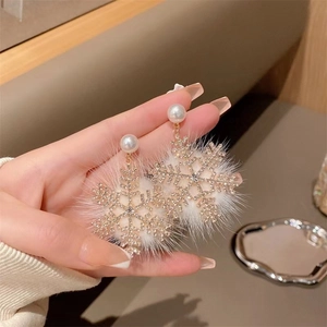 Sparkling snowflake earrings with zircon and pearls held in hand for Christmas gift