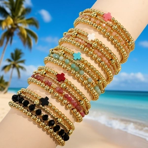 Bohemian summer beaded bracelet set with gold beads and colorful cross charms on beach