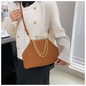 Detail of a brown quilted leather handbag with gold chain handle and shoulder strap