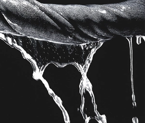 Macro shot of twisted absorbent microfiber towel wringing out water with dramatic lighting