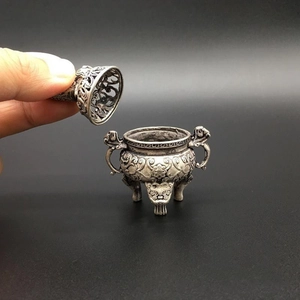 Macro detail of a mini antique incense burner with hollow floral patterns and three legs