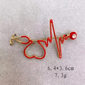 Gold-plated stethoscope EKG brooch with red enamel and rhinestone accent, size 6.4x3.6cm