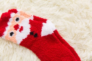 Detail of red and white Christmas fuzzy socks with cute Santa Claus plush embroidery