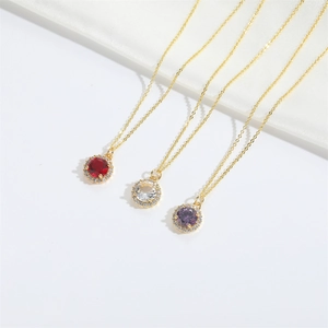 Close-up of gold chain necklaces with round red, clear, and purple zircon pendants