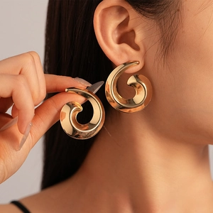 Close-up of elegant gold spiral geometric earrings with high gloss metallic finish
