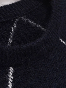 Dettaglio macro del maglione a rombi blu navy con morbida trama in mohair