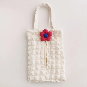 Detail of white bubble fabric tissue holder with a knitted blue and pink flower