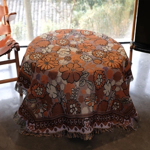 Vintage bohemian round picnic blanket with floral patterns and fringe details in outdoor setting
