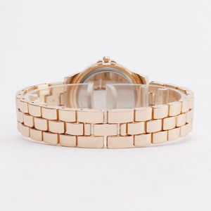 Montre en métal or rose avec bracelet à maillons et fond de boîtier rond sur support