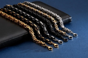 Close-up of Byzantine stainless steel chains in gold, black, and silver with lobster clasps