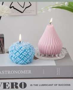 Macro shot of blue knit textured sphere candle and pink geometric diamond pear candle