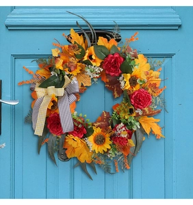 Dettaglio ghirlanda autunnale con girasoli, foglie di acero e fiocco su porta blu
