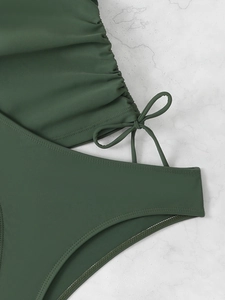 Detail of dark green ribbed swimwear fabric with side ruching and delicate bow tie detail