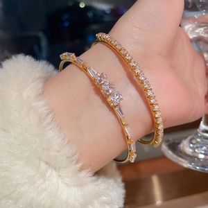 Close-up of 18K gold plated square zircon bracelets worn with white faux fur sleeve