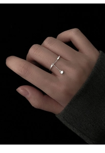 Detailed view of silver chain ring with a dangling bead charm on a hand background