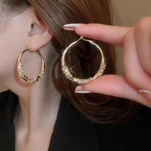 Detailed view of large gold twisted hoop earrings with shimmering crystal pavé setting